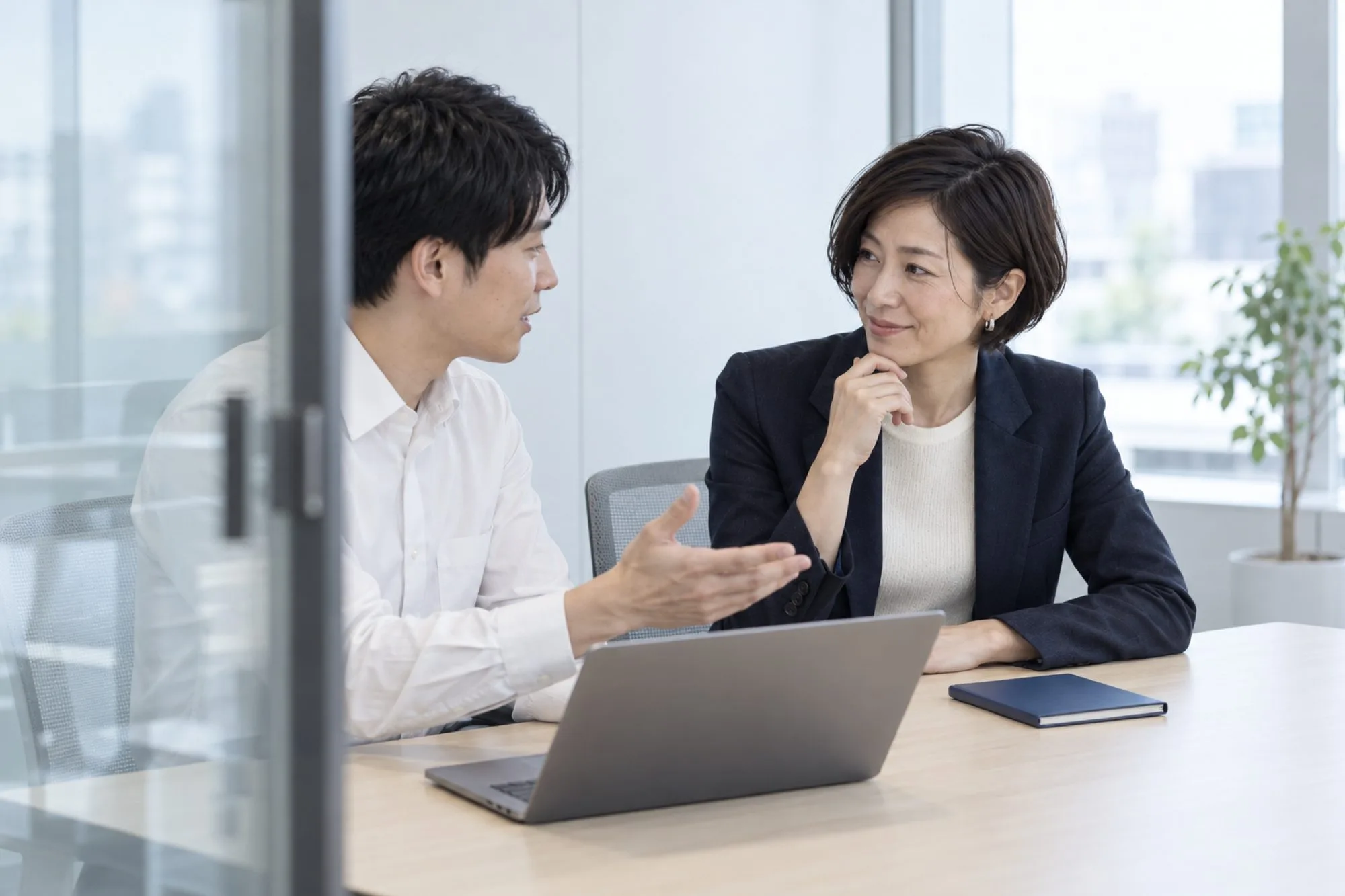 会議室で、営業マネージャーが若手の営業担当の話を聞く週 1 回の 1 対 1 の面談（イメージ・見本）